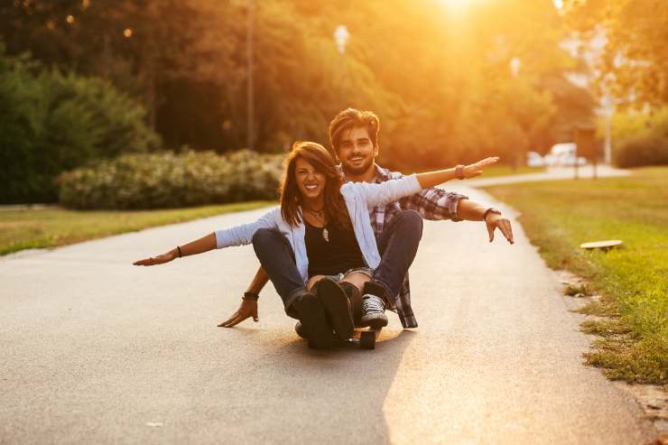 coppia felice sullo skate in un parco 