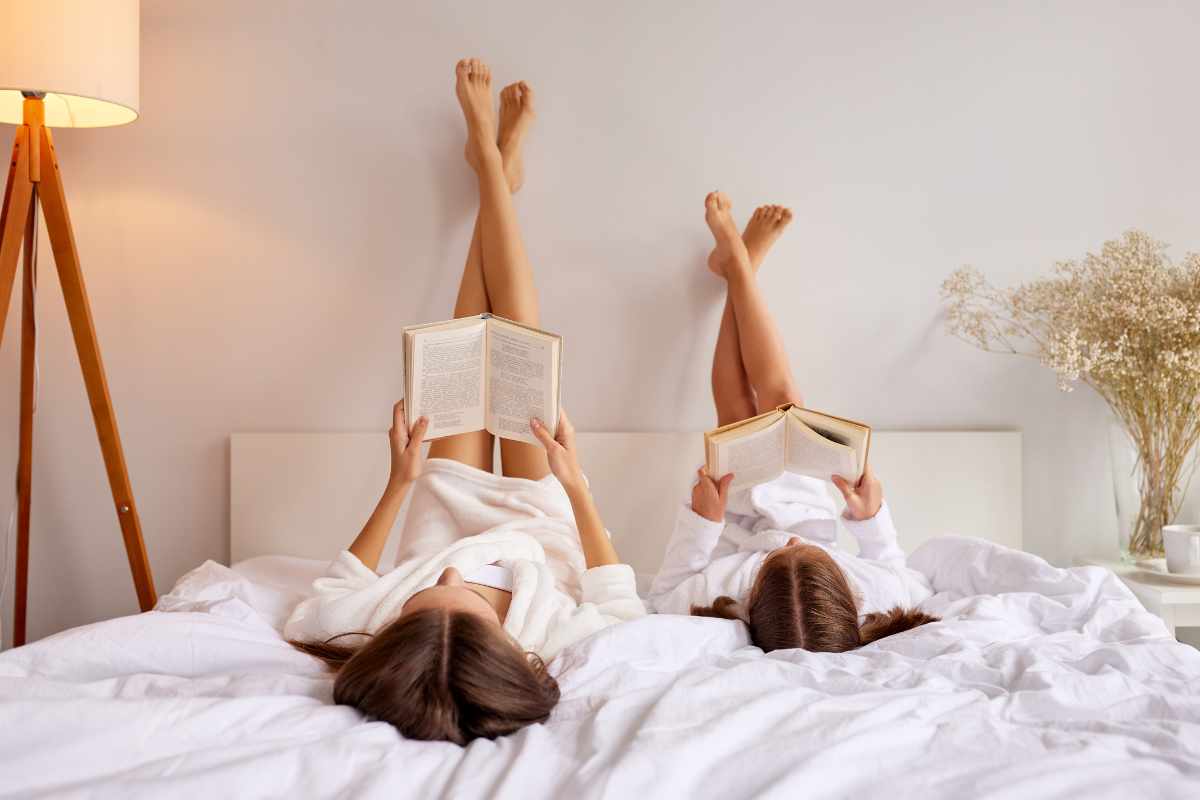 mamma e figlia leggono libri sul letto tenendo le gambe incrociate