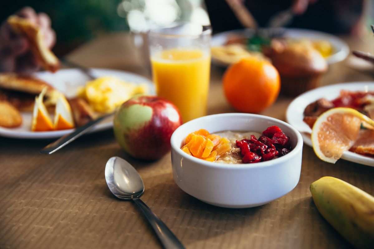 tavola apparecchiata con frutta fresca, porridge e spremuta