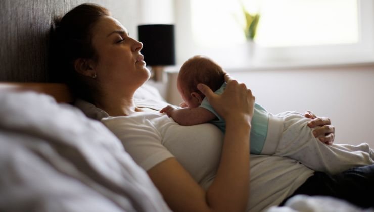Donna sdraiata con neonato in braccio