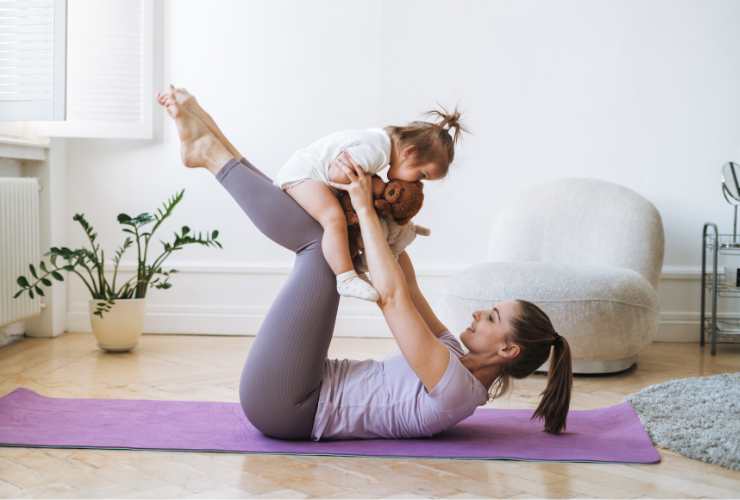 donna che fa fitness in casa con sua figlia piccola