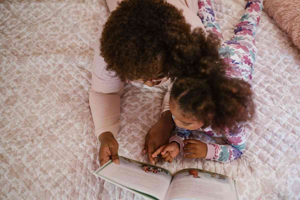 madre e figlia che leggono libro sul letto