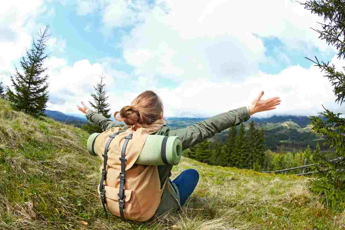 ragazzo con braccia aperte che guarda la montagna