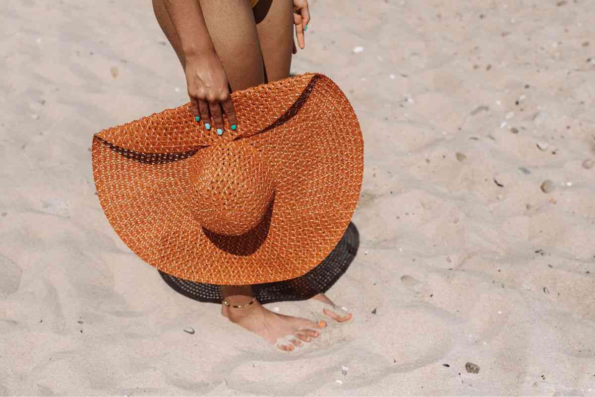 Donna in spiaggia con cappello di paglia enorme