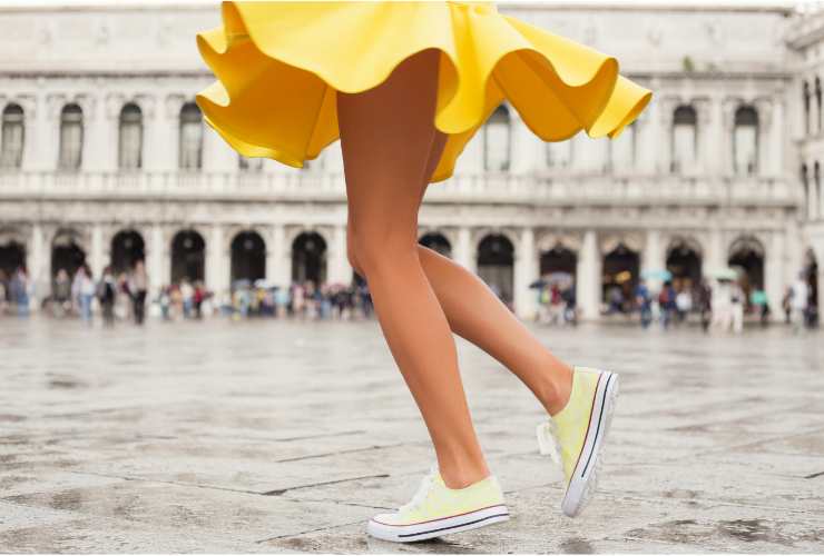 gambe donna con minigonna e sneakers gialle