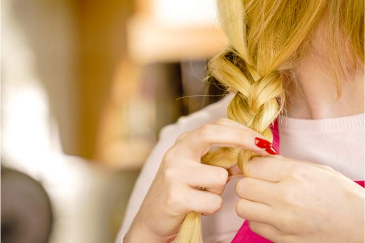 donna che fa treccia sui capelli biondi