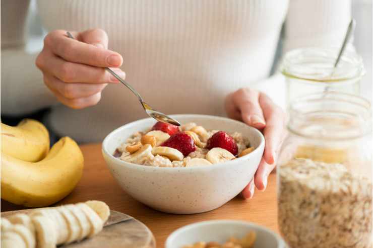 donna che mangia ciotola di avena e frutta fresca