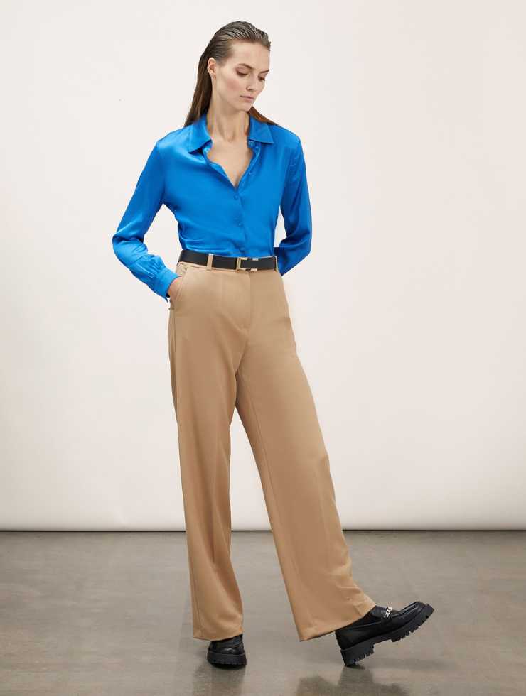 modella con camicia azzurra e pantaloni palazzo beige