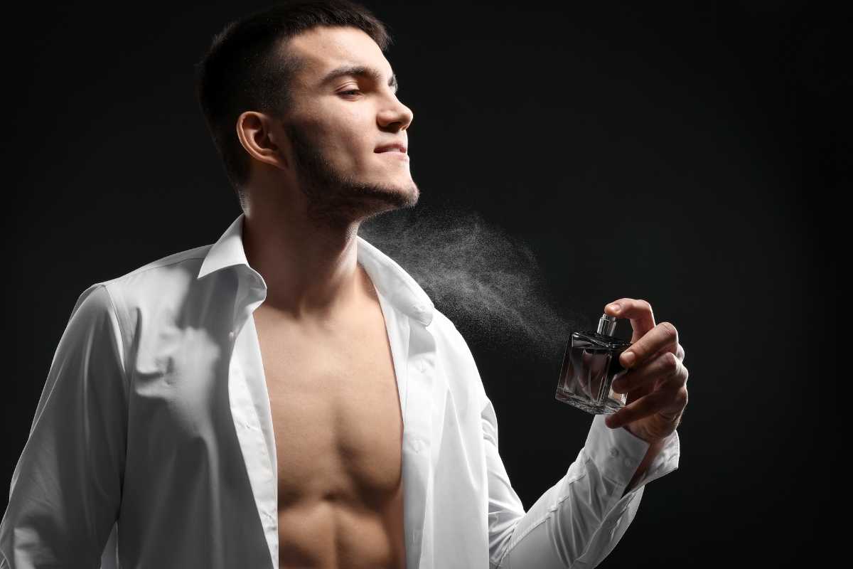 uomo con camicia aperta che spruzza il profumo