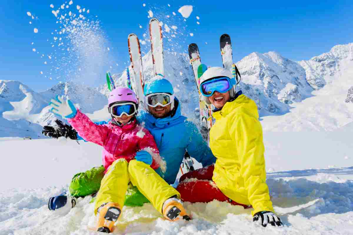 famiglia seduta sulla neve in settimana bianca